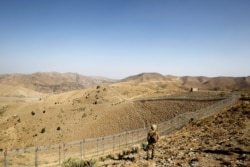 FILE - A soldier stands guard along the border fence outside the Kitton outpost on the border with Afghanistan in North Waziristan, Pakistan, Oct. 18, 2017.