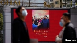 资料照片: 上海行人走过一个显示中国领导人习近平的大屏幕。(2020年3月23日)