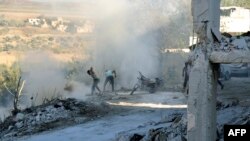 Sirijci koriste zemlju i prašinu da bi ugasili vatru na mestu navodnog vazdušnog udara u Džisr al Šuguru, u provinciji Idlib, 4. septembra 2018.