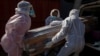 Funeral home workers in protective suits carry the coffin of a woman who died from COVID-19 into a hearse in Katlehong, near Johannesburg, South Africa, 