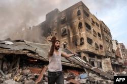 Seorang pria berada di luar gedung yang runtuh akibat pemboman Israel di Kota Gaza pada 11 Oktober 2023. (Foto: AFP)