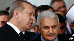Turkey's President Recep Tayyip Erdogan (L) talks to Turkey's Prime Minister Binali Yildirim (R) as they attend the inauguration ceremony of the Melike Hatun mosque in Ankara, Turkey, Oct. 27, 2017. 