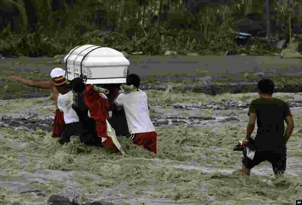 Relatives cross a river to bury their loved one, who died in a flash flood caused by Typhoon Bopha in New Bataan township, Compostela Valley, Philippines, December 6, 2012.