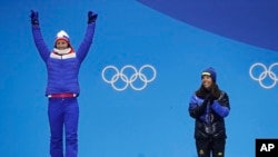 Charlotte Kalla (Swedia), tengah, peraih medali emas pertama Olimpiade Musim Dingin di PyeongChang 2018 untuk kategori Women's cross-country 7.5/7.5 kilometer skiathlon, bertepuk tangan seusai Marit Bjoergen (Norwegia) menerima medali peraknya, pada upacara penyerahan medali, 10 Februari 2018. 