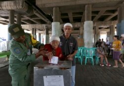 Para petugas membantu perempuan lansia memasukkan surat suara di sebuah tempat pemungutan suara di Jakarta, 19 April 2017.