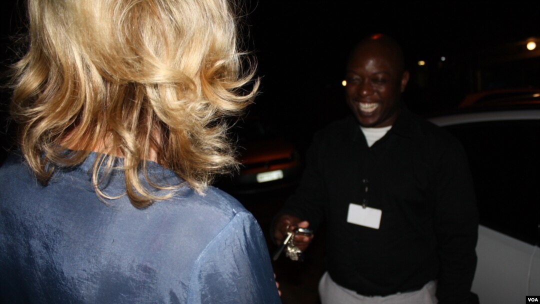A woman (left) hands her car keys to Scooter Angels driver Blessing Mhango. Growing numbers of South Africans are using services such as his, Tuesday, Sept. 17, 2015. (photo: D. Taylor)