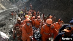 Members of National Disaster Response Force (NDRF) carry the body of a victim after recovering it from the debris during a rescue operation outside a tunnel after a part of a glacier broke away, in Tapovan in the northern state of Uttarakhand, India, Febr