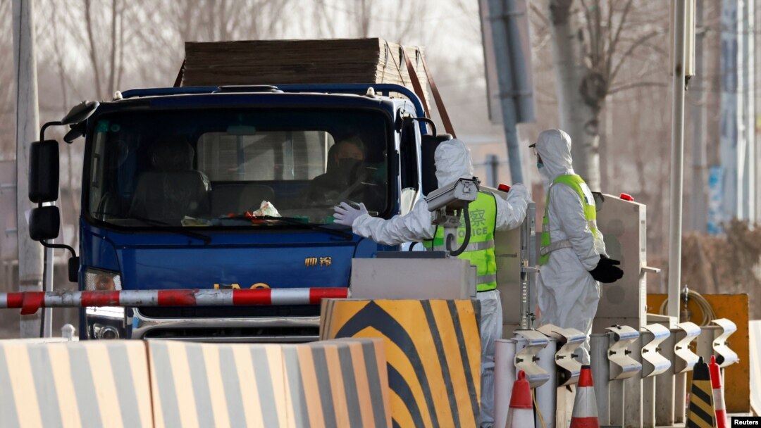 身穿防護服的警察在河北省通往北京的一個道路檢查站攔住一輛卡車。（2021年1月12日）