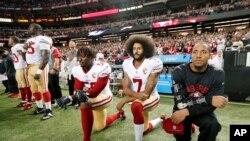 FILE - San Francisco 49ers quarterback Colin Kaepernick (7) and outside linebacker Eli Harold (58) kneel during the playing of the national anthem before an NFL football game against the Atlanta Falcons in Atlanta.