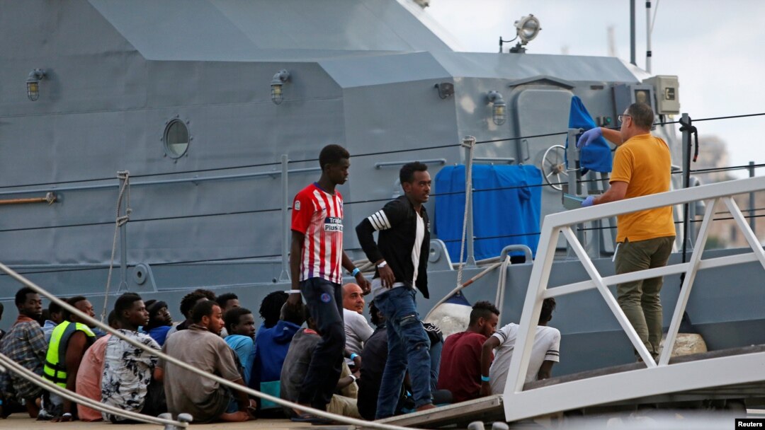 FILE - A police officer speaks to rescued migrants after they arrived on an Armed Forces of Malta patrol boat in Valletta's Marsamxett Harbor, Malta, Sept. 21, 2019. 