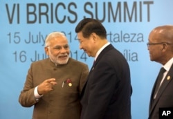 印度总理莫迪和中国国家主席习近平在巴西出席金砖五国会议领导人合影期间交谈。（2014年7月15日）