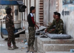 Turkey-backed Syrian rebel fighters chat in the border town of Tal Abyad, Syria, Oct. 18, 2019.