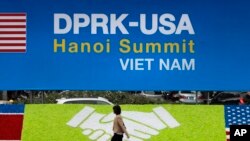 一名妇女走过越南首都河内国际媒体中心的美国和朝鲜旗帜。 2019年2月25日