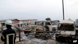 Tampak beberapa kendaraan yang terbakar di luar penjara di Kinshasa, Kongo, dalam foto yang diambil pada 17 Mei 2017. Kelompok sektarian Kristen menyerbu penjara tersebut untuk membebaskan pentolan kelompok mereka. (Foto: AP/John Bompengo)