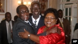 IN GOOD TIMES: Zimbabwean President Robert Mugabe, left, celebrates with newly sworn-in vice presidents Joyce Mujuru, right, and the late Joseph Msika, center, State House, Harare, Oct. 2008 file photo.