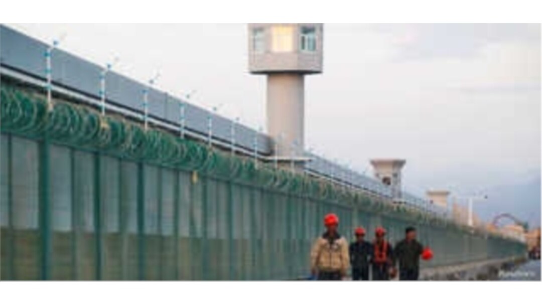 FILE - Workers walk by the perimeter fence of what is officially known as a vocational skills education center in Dabancheng in Xinjiang Uighur Autonomous Region, China, Sept. 4, 2018.