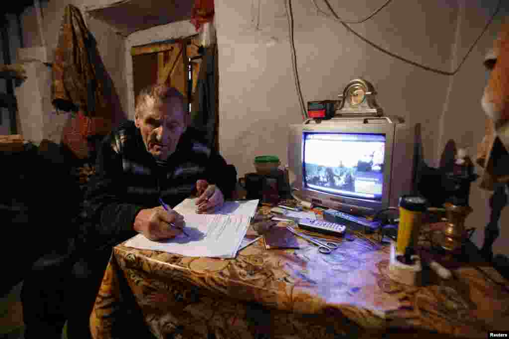 Seorang pria mengisi formulir pendaftaran sebelum memberikan suaranya dalam kotak pemilihan keliling dalam referendum di desa Pionerskoye, dekat Simferopol, Krimea, Ukraina, 16 Maret 2014.