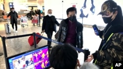 FILE - A man passes through a health screening checkpoint at Wuhan Tianhe International Airport in Wuhan, in southern China's Hubei province, Jan. 21, 2020. 