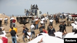 Warga Palestina mengambil karung-karung berisi tepung dari sebuah truk bantuan dekat pos pemeriksaan Israel di Kota Gaza, 19 Februari 2024. (Foto: Kosay Al Nemer/Reuters)