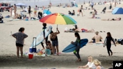 Beachgoers converge under a pier in Huntington Beach, Calif., April 30, 2020.