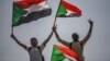 Sudanese protesters flash the victory sign and wave national flags during a rally outside the army headquarters in the capital, Khartoum, April 19, 2019.