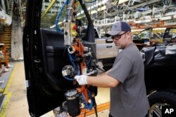 FILE - A worker installs the front doors on a 2018 Ford F-150 truck being assembled at the Ford Rouge assembly plant, in Dearborn, Michigan, Sept. 27, 2018.
