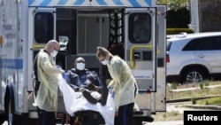 Osoblje hitne pomoći prebacuje pacijenta sa koronavirusom u kola hitne pomoći u Njujorku, 26. marta 2020. 