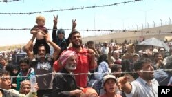 FILE - Syrian refugees gather at the Turkish border as they flee intense fighting in northern Syria between Kurdish fighters and Islamic State militants in Akcakale, southeastern Turkey, June 15, 2015.