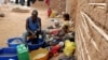 FILE - A Ugandan man cleans his clothes at the Makerere Kivulu slums in Kampala.