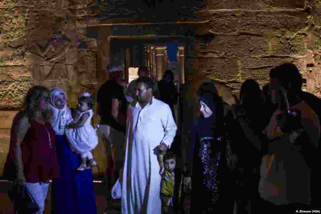 An Egyptian woman holding a baby poses with a tourist at the Luxor temple, in Luxor, Egypt, Sept. 9, 2017. (H. Elrasam/VOA)