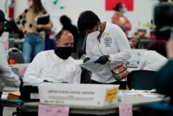 A worker checks with an election supervisor at the central counting board, in Detroit, Michigan, Nov. 4, 2020.