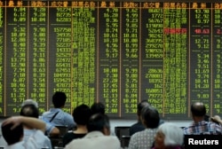 FILE - Investors look at stock information on an electronic board at a brokerage house in Hangzhou, Zhejiang province, Aug. 25, 2015.