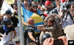 FILE - Demonstrators clash with counterprotesters at the entrance to Lee Park in Charlottesville, Va., Aug. 12, 2017.