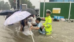 河南省鄭州市一名交通警察用一條繩子幫助居民過洪水湍急的街道。 （2021年7月20日）