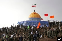 Members of the Basij, the paramilitary unit of Iran's Revolutionary Guard, gather around a replica of Jerusalem's gold-topped Dome of the Rock mosque as one of them waves an Iranian flag from on top of the dome during a military exercise, Nov. 20, 2015.