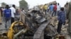People look at damage in a market area after a bomb explosion in Ajilari-Gomari near the city's airport, Maiduguri, Borno State, March 2, 2014.