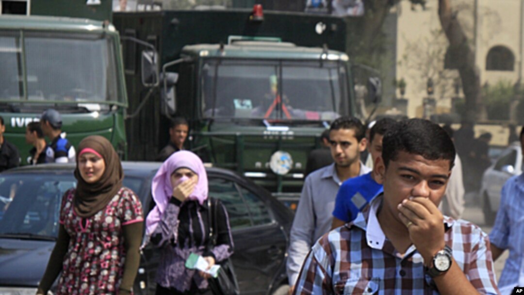 Egyptians cover their faces to avoid tear gas vapor as they walk at the site of clashes between protesters and anti-riot policemen near the Israeli Embassy in Cairo, Egypt, Sept. 10, 2011.