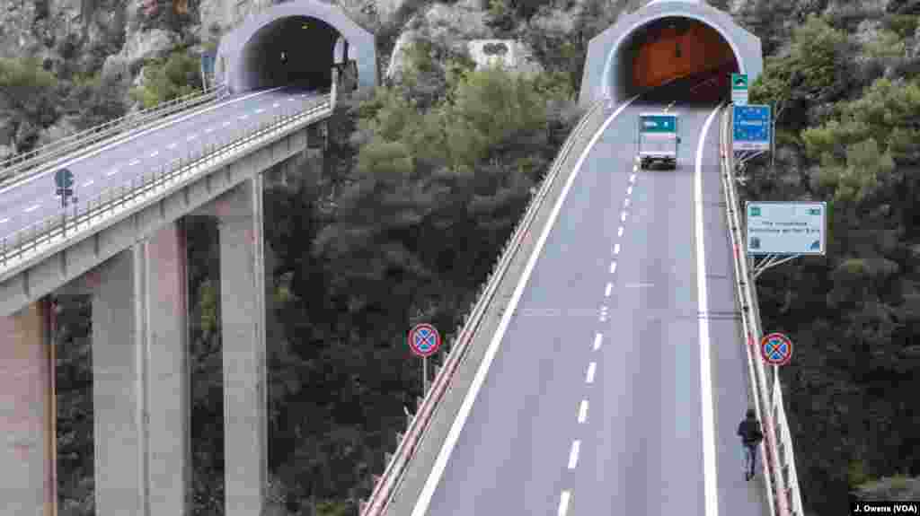 A man runs across a motorway off the so-called Pass of Death in Italy, in an attempt to get into France. An Eritrean woman died on this stretch of road last year after being hit by a truck.