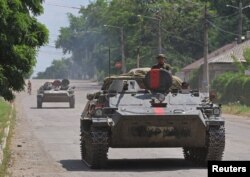 Tentara pro-Rusia mengendarai kendaraan militer di jalanan kota Lysychansk, provinsi Luhansk, Ukraina timur Senin (4/7).