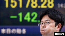 东京有人走过证券公司显示股票指数的电子告示牌
