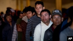Kaum migran asal Honduras tampak antri untuk mendapatkan makan pagi dalam sebuah gudang kosong yang membuka pintu-pintunya untuk kaum migran di tengah kota Tijuana, Meksiko, Selasa, 18 Desember 2018 (foto: AP Photo/Moises Castillio)