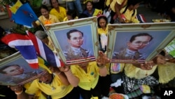 FILE - Supporters hold a portrait of Thai King Bhumibol Adulyadej in Bangkok, Thailand, May 10, 2015.