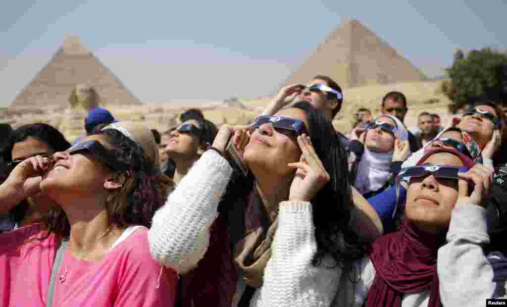 Orang-orang mengamati gerhana matahari sebagian di dekat Piramid Giza, di pinggiran Kairo, Mesir. Gerhana matahari total hanya dapat terlihat di Kepulauan Faroe dan Svalbard di Norwegia.