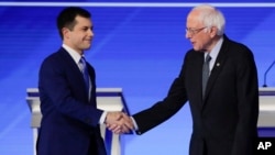 Democratic presidential candidates former South Bend Mayor Pete Buttigieg and Sen. Bernie Sanders, I-Vt., shake hands on stage Friday, Feb. 7, 2020, before the start of a Democratic presidential primary debate hosted by ABC News, Apple News, and…