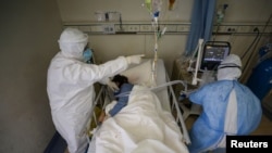 Medical workers in protective suits attend to a patient inside an isolated ward of Wuhan Red Cross Hospital in Wuhan, the epicenter of the novel coronavirus outbreak, in Hubei province, China, Feb. 16, 2020.