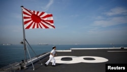Yuma Osaki, a navigator, runs back to her post after a flag-raising ceremony on the flight deck of Japanese helicopter carrier Kaga before its departure for naval drills in the Indian Ocean, Indonesia, Sept. 22, 2018.