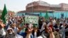 FILE - A supporter of the Tehreek-e-Labaik Pakistan, an Islamist political party, holds a sign, which reads in Urdu, "remove Zahid Hamid" during a sit-in protest along a main road in Karachi, Nov. 27, 2017. 