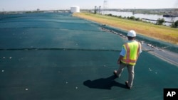 Manajer proyek, Jeff Richey, berjalan di antara penutup kolam pembuangan abu batubara Basin B yang tidak berpori-pori di sepanjang Sungai Elizabeth di Chesapeake, Va, Senin, 27 Juni 2016 (foto: AP Photo/Steve Helber)