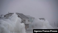 File - Waves crash over oceanfront homes during a nor’easter in Scituate, Massachusetts on January 29, 2022.