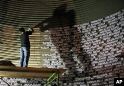 Seorang petugas memasang nama-nama korban tsunami 2004 di Museum Tsunami di Banda Aceh menjelang peringatan 10 tahun bencana tersebut.